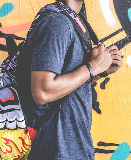 Student with backpack in front of mural