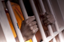 An incarcerated person with his hands on the bars